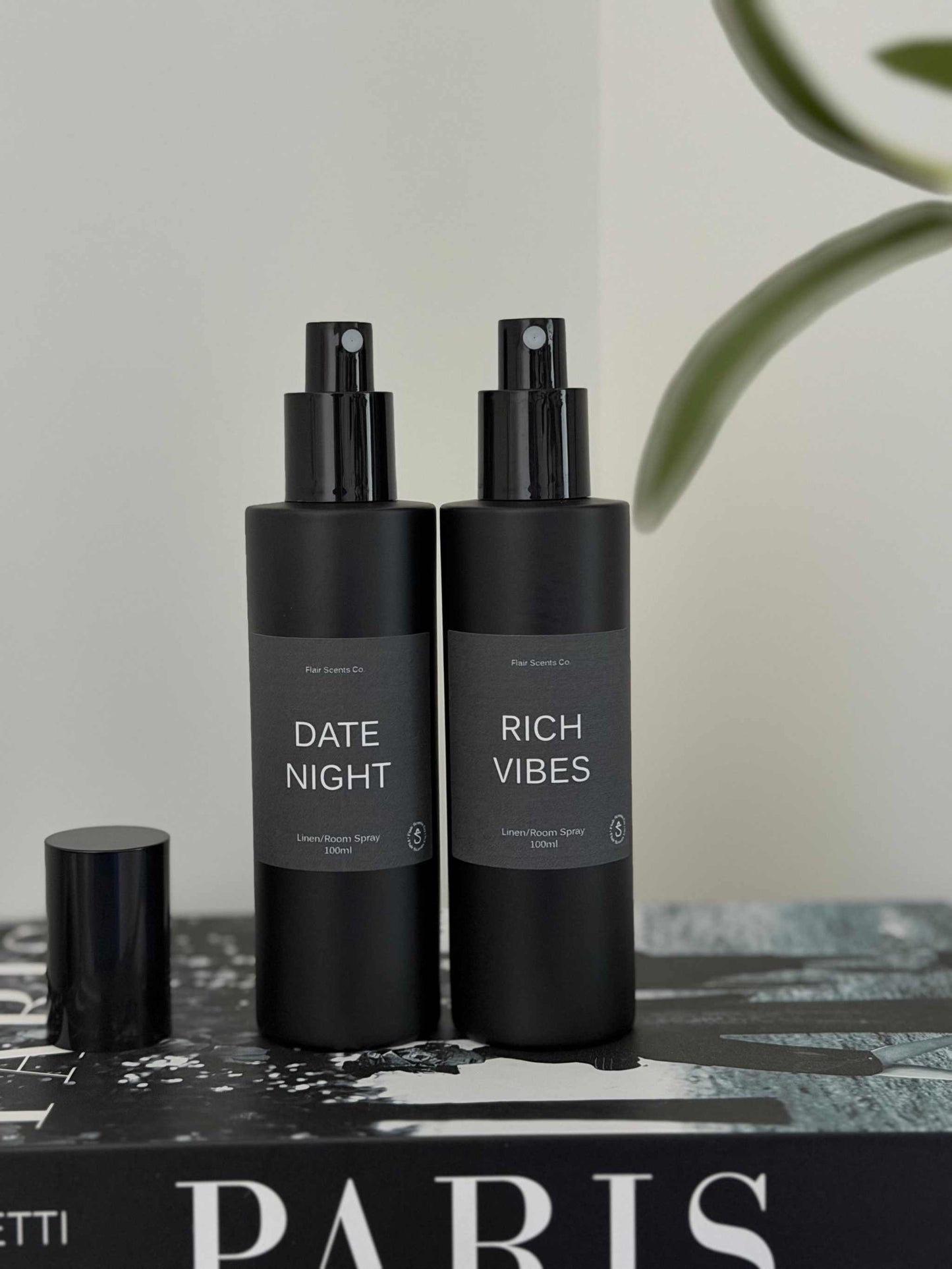 Room/Linen Spray bundle with Date Night and Rich Vibes scents in black bottles on book.