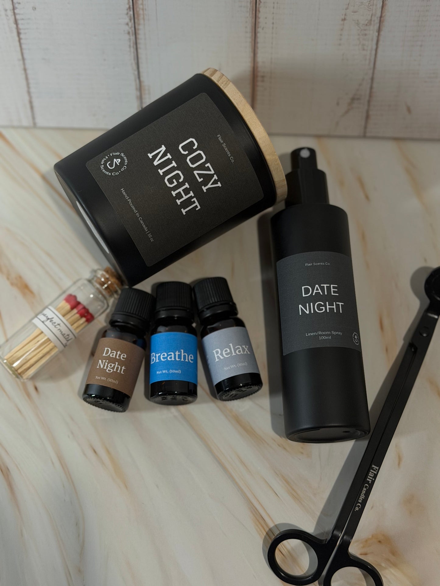 Evening Reset Bundle night routine self-care set featuring a calming candle, room spray, essential oil, wick trimmer, and match sticks arranged in a peaceful home setting.