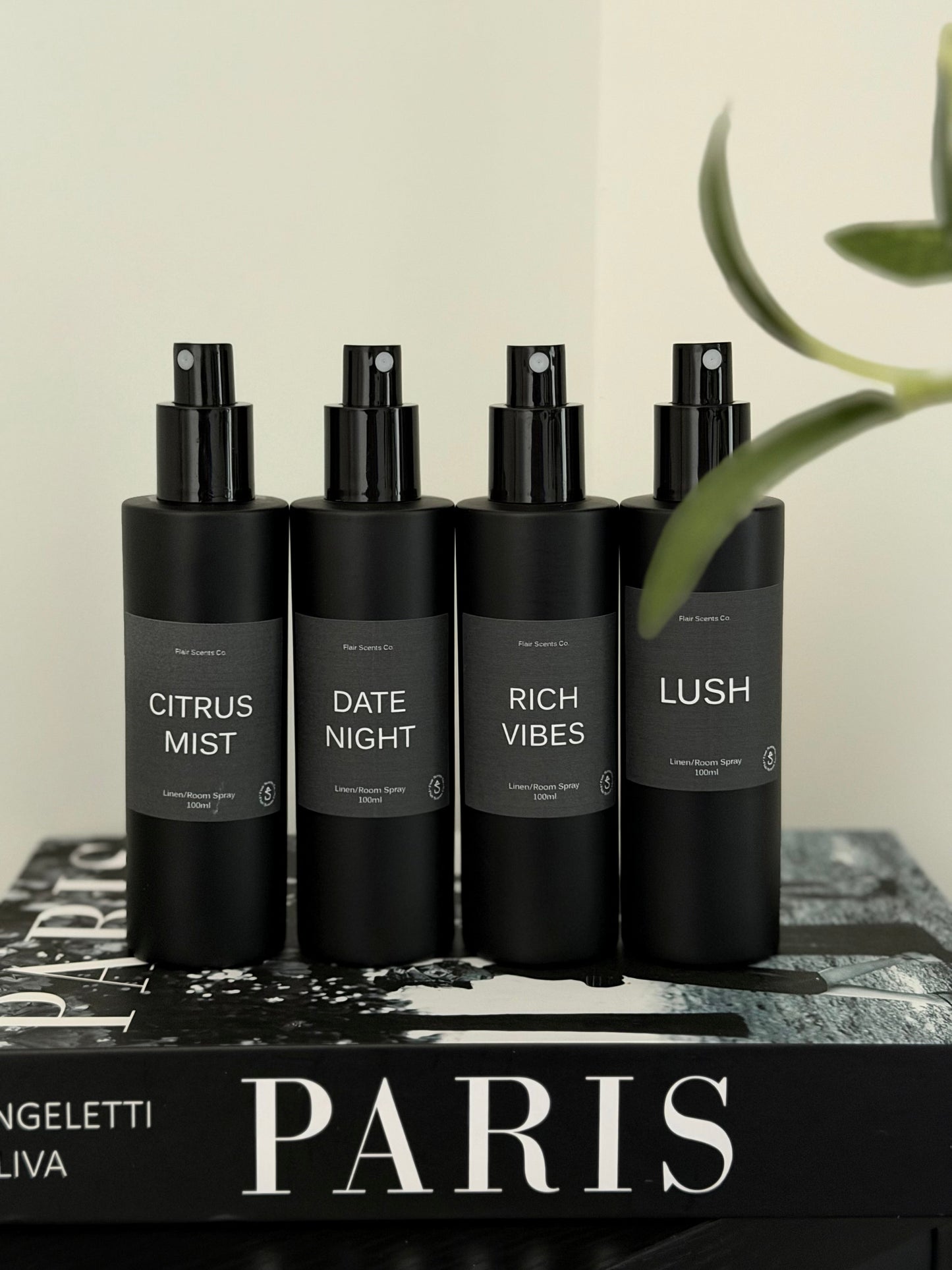 Room/Linen Spray bundle with four black bottles featuring Citrus Mist, Date Night, Rich Vibes, and Lush scents on a Paris book