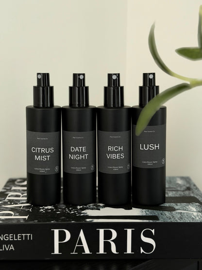 Room/Linen Spray bundle with four black bottles featuring Citrus Mist, Date Night, Rich Vibes, and Lush scents on a Paris book