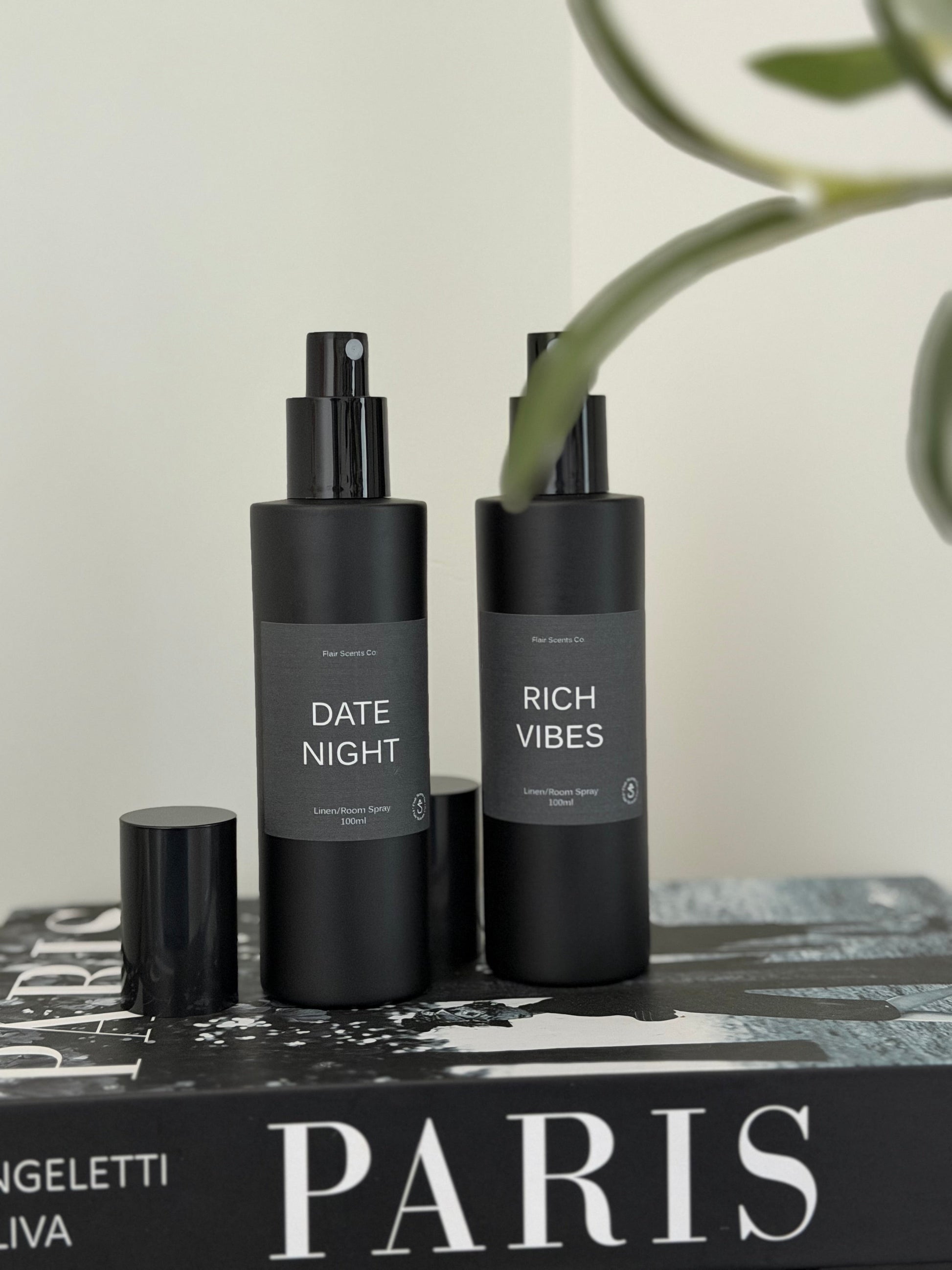 black matte bottles of room linen spray on book titled Paris with plant in background