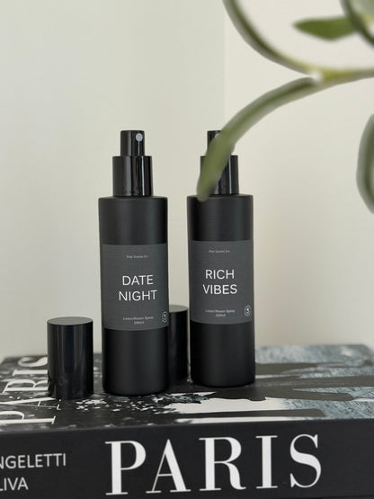 black matte bottles of room linen spray on book titled Paris with plant in background