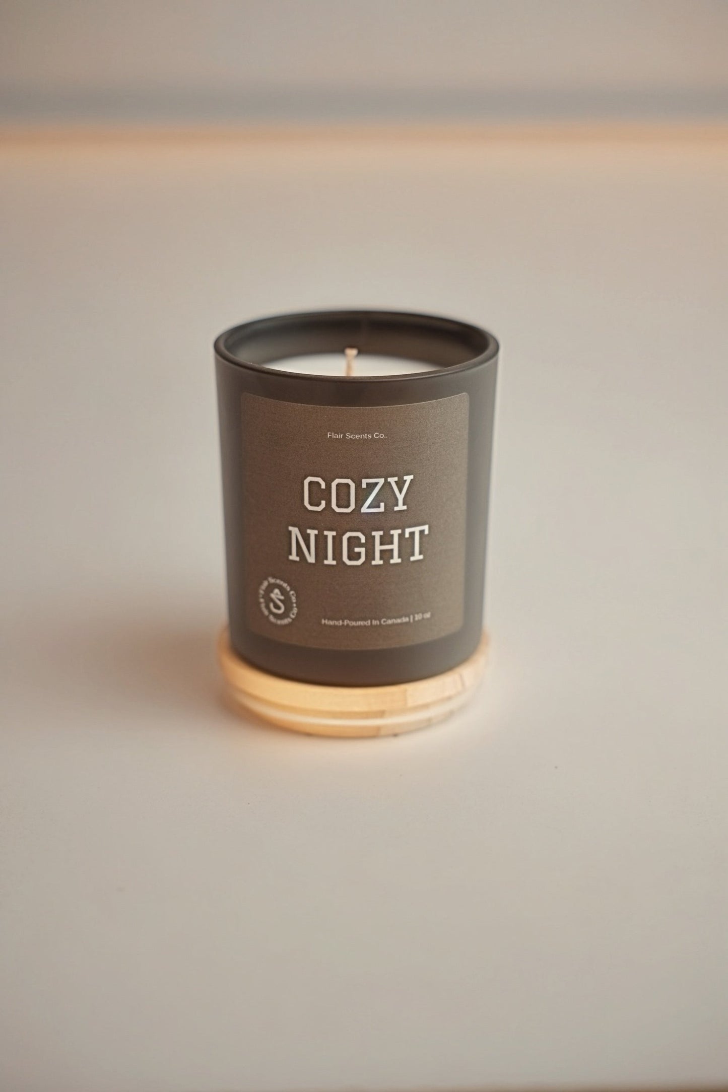 Cozy Night luxury soy candle with sandalwood oceanic patchouli and earthy musk in black jar on wooden base